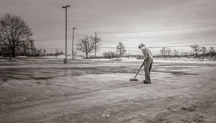 man with broom sweeping black and white out with the old